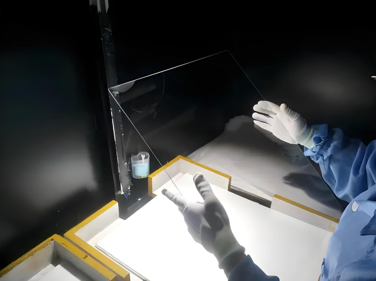 Technician inspecting ITO coated ultra-clear glass during solar panel production process